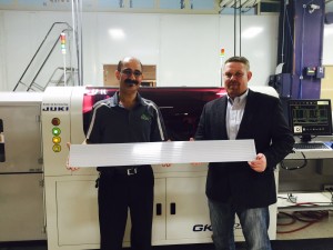 Emmil Makram (left), SMT Supervisor, and Deist hold a 4 ft. LED panel that consists of 10 separate LED PCBs. They are standing in front of the Juki/GKG PMax printer – which is only a few worldwide that is capable of producing 4 ft. panels in large quantities.